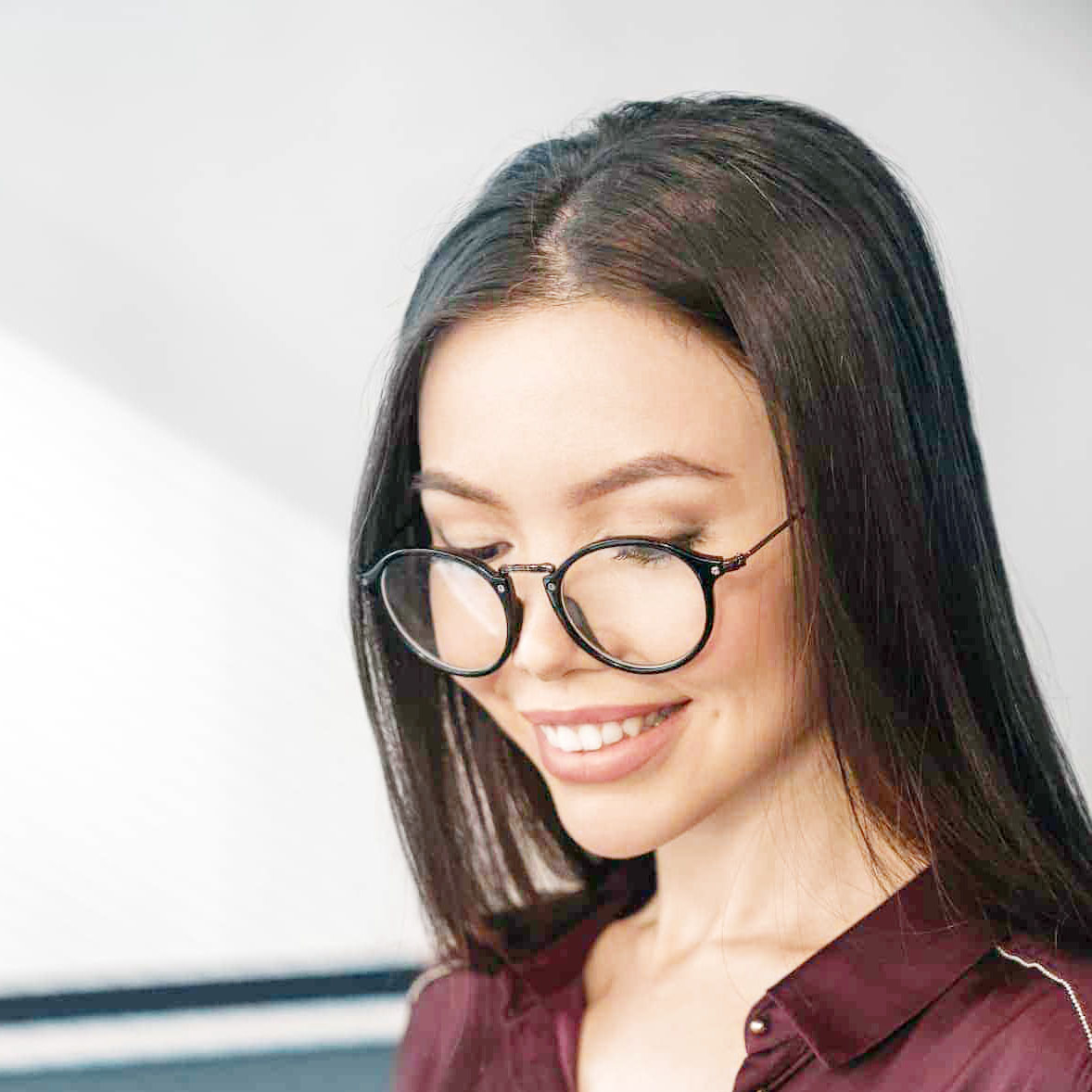 Mulher sorrindo em sala de estar, representando a satisfação com o catálogo sob demanda e canais infantis do IPTV.